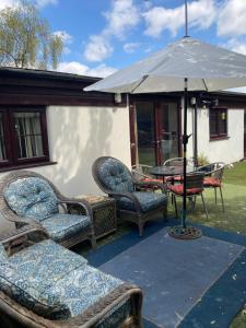 eine Gruppe von Stühlen und ein Sonnenschirm auf einer Terrasse in der Unterkunft 2 bedrooms Bell Cottage in Hoddesdon