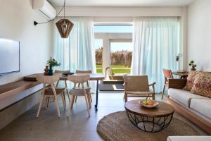 ALERÓ Seaside Skyros Resort في سكيروس: غرفة معيشة مع أريكة وطاولة وكراسي