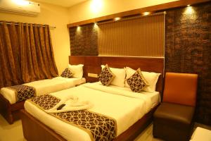 a hotel room with two beds and a chair at Horizon Inn in Chennai
