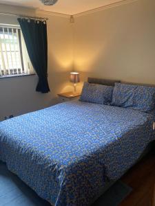 ein Schlafzimmer mit einem Bett mit einer blauen Bettdecke in der Unterkunft 2 bedrooms Bell Cottage in Hoddesdon