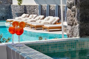 two wine glasses sitting on a ledge next to a swimming pool at Amara Suites Santorini in Kamari