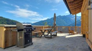 a patio with a grill and a picnic table and mountains at Panorama Berg Chalet in Großkirchheim