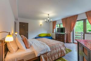 a bedroom with a king sized bed and a television at Vila Trubadur - Adults Only in Bran