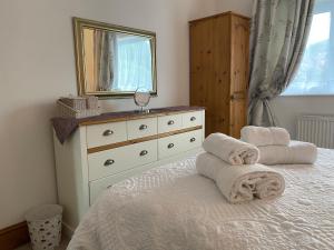 a bedroom with a bed with a dresser and a mirror at Ashbourne Holiday Homes in Ashbourne