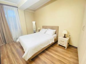 MG Apartments in Tbilisi في تبليسي: غرفة نوم بسرير ابيض كبير وموقف ليلي