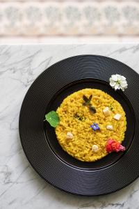 a black plate with yellow rice on a table at Pałac Ciekocinko Hotel Resort & Wellness in Ciekocinko