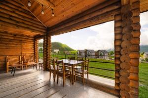 a wooden porch with a table and chairs and a view of a field at Snow Time Eco Chalet in Gudauri