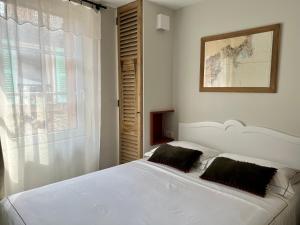 1 dormitorio con cama blanca y ventana en Les Petits Volets 2, en Antibes
