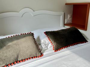 ein weißes Bett mit roten und schwarzen Kissen darauf in der Unterkunft Les Petits Volets 2 in Antibes