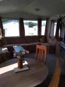 a living room with a table and a couch at Private caravan situated at Parkdean Holiday Resort St Margaret's at Cliffe number 18 in St Margarets at Cliff