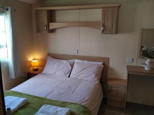 a bedroom with a bed with white sheets at Private caravan situated at Parkdean Holiday Resort St Margaret's at Cliffe number 18 in St Margarets at Cliff