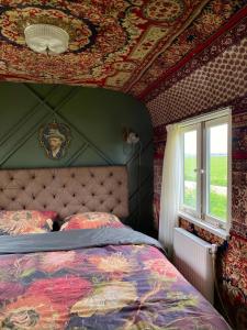 a bedroom with a bed and a window at Slapen tussen de schapen in pipowagen de Ome Jan in Zennewijnen