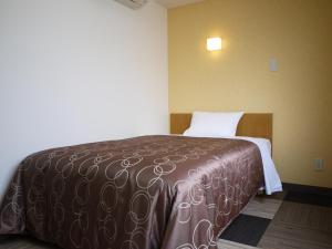 een bed in een hotelkamer met een bruine deken bij Hotel Select Inn Shikoku Chuo in Shikokuchuo