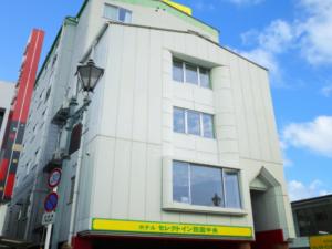 een wit gebouw met een straatlicht ervoor bij Hotel Select Inn Shikoku Chuo in Shikokuchuo