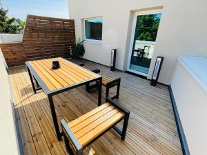 een houten terras met een tafel en twee banken bij Hotel Vesiroos in Pärnu