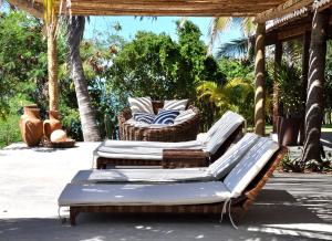 3 chaises en osier sur une terrasse avec des palmiers dans l'établissement Casa Mandakarú, à Icapuí