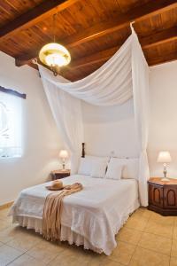 a bedroom with a white bed with a wooden ceiling at ViLLA SYMONE in Afiartis