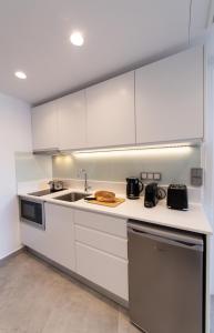uma cozinha com armários brancos e um lavatório em Azul Apartments em Nydri