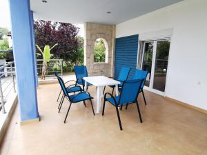a patio with a white table and blue chairs at Nick House in Pefkohori