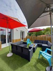 a patio with umbrellas and chairs and a table at Gîte "Chez Marcel et Cie" - 8 mn du Puy du Fou in Les Herbiers
