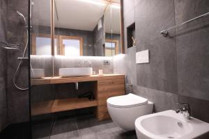 een badkamer met een toilet, een wastafel en een spiegel bij CASA IBEX - Piscina - Sauna - Baby Club in Cavalese