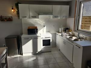 kuchnia z białymi szafkami, zlewem i kuchenką w obiekcie Gîte de la Vallée w mieście Genneville