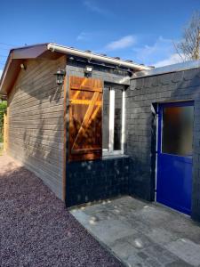 een gebouw met een blauwe deur en een garage bij Gîte de la Vallée in Genneville