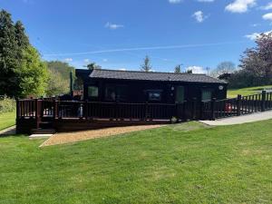 una cabina nera con una recinzione in legno nell'erba di Lakeview Lodge, Builth Wells no tradesmen allowed a Builth Wells