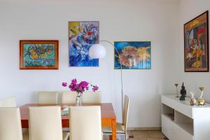 a dining room with a table and chairs and paintings at Appartamento Casa dell'Olivo in Marina di Pescoluse