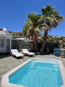 una piscina con 2 palmeras y una casa en Efthymia Suites, en Faros