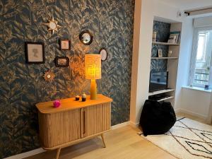 een kamer met een tafel met een lamp erop bij Le coquillage magique in Granville