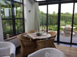 una sala da pranzo con tavolo, sedie e ampie finestre di Gîte des Grandsarts a Chimay