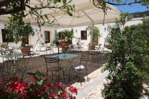 eine Terrasse mit Tischen und Stühlen unter einem Sonnenschirm in der Unterkunft Hotel Villa Lampedusa in Palermo