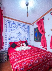 a white bed with a red and white striped bedspread at Dar Touijar in Chefchaouen