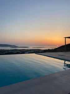 a swimming pool with the sunset in the background at Sun House Paros in Kampos Paros