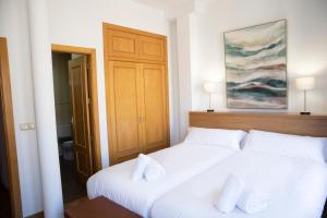 Apartamento Lomeña في غرناطة: سريرين في غرفة مع وسادتين بيضاء