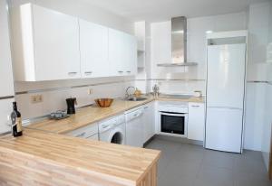 Apartamento Lomeña في غرناطة: مطبخ بخزائن بيضاء وثلاجة بيضاء