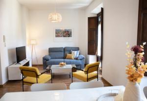 Apartamento Lomeña في غرناطة: غرفة معيشة مع أريكة زرقاء وكراسي صفراء