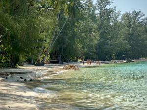 a beach with trees and people on the sand and water at Coconut Beach Bungalows in Chaloklum