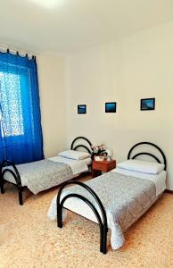 three beds in a room with blue curtains at Casa Anto in Lezzeno
