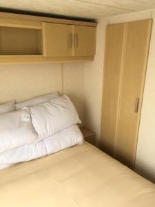 a bed with white pillows in a small room at Sea Breeze at Winthorpe Skegness in Skegness