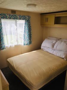 ein kleines Schlafzimmer mit einem Bett und einem Fenster in der Unterkunft Sea Breeze at Winthorpe Skegness in Skegness