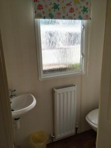 uma casa de banho com um lavatório e uma janela em Sea Breeze at Winthorpe Skegness em Skegness