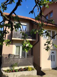 a house with a balcony and a table in front of it at Apartmani MALINA in Vrnjačka Banja