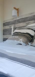 Bett mit einem Kopfteil aus Holz und Kissen in der Unterkunft gîte Les Châtaigniers entre terre et mer in Pleucadeuc