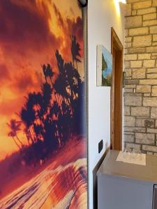 a painting of a beach with palm trees on a wall at Palermiti Luxury Rooms in Himare