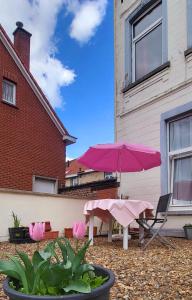 eine Terrasse mit einem rosa Regenschirm, einem Tisch und Stühlen in der Unterkunft Cozy studio near Nato in Brüssel