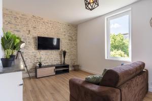 uma sala de estar com um sofá e uma televisão na parede em Le Liondor em Montélimar
