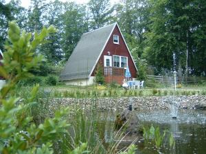 une maison rouge avec un étang devant elle dans l'établissement Ferienpark Rosstrappe, à Thale