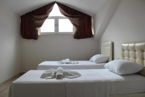 two beds in a room with a window at Tebriz Apart in Kemer